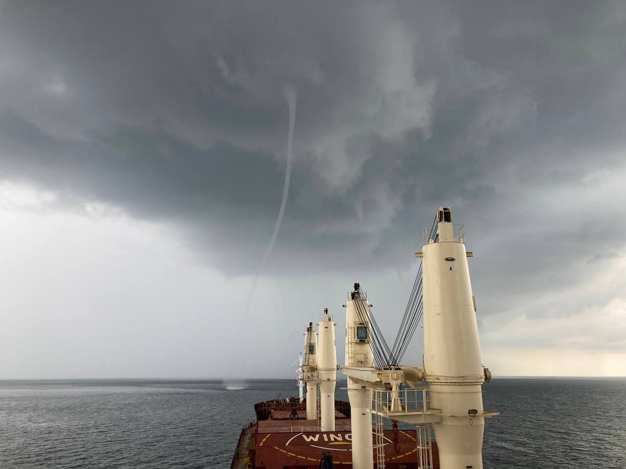 Палубные краны и тёмные облака над морем